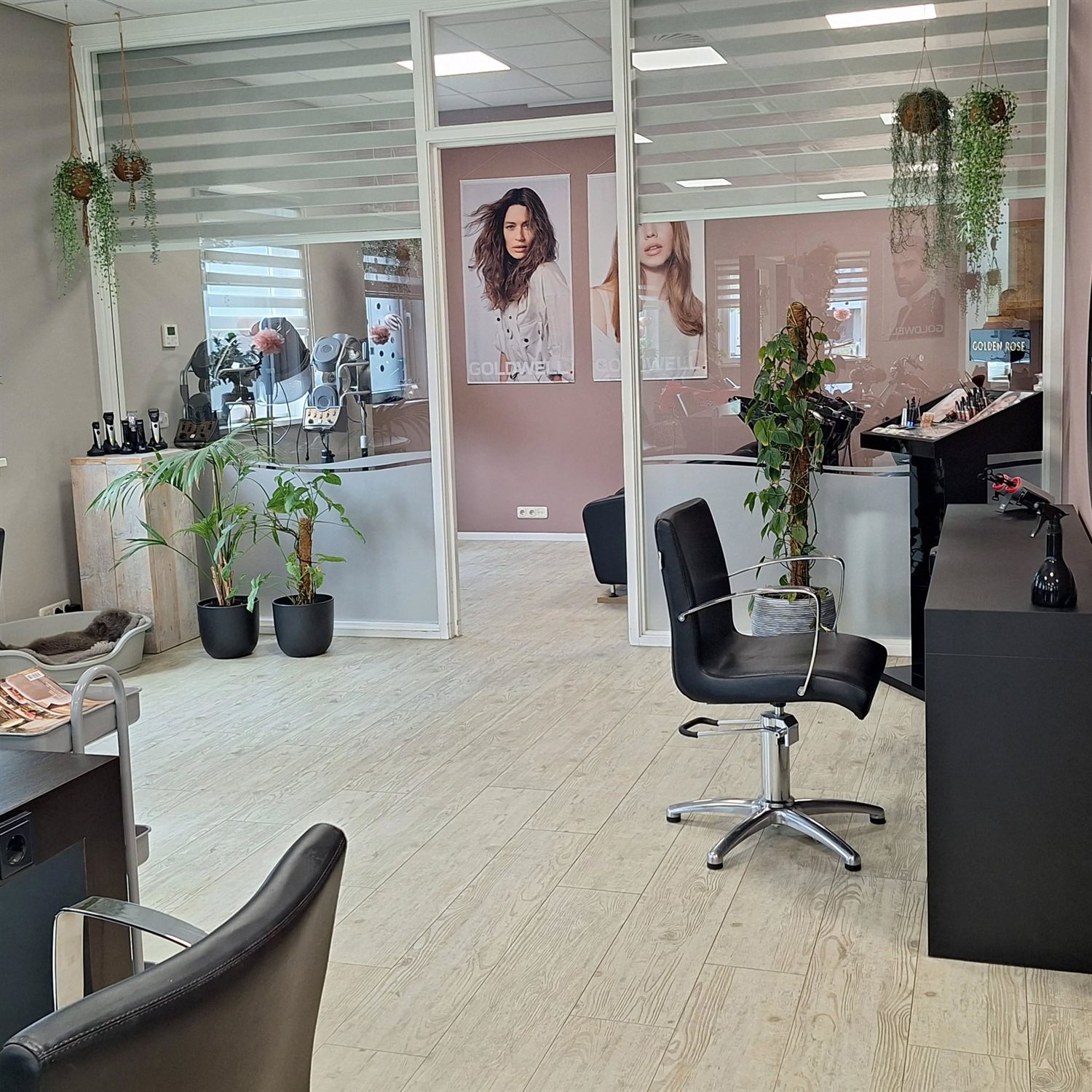 Het warme interieur van Kapsalon Trijnie met roze muren, planten en kappersstoelen
